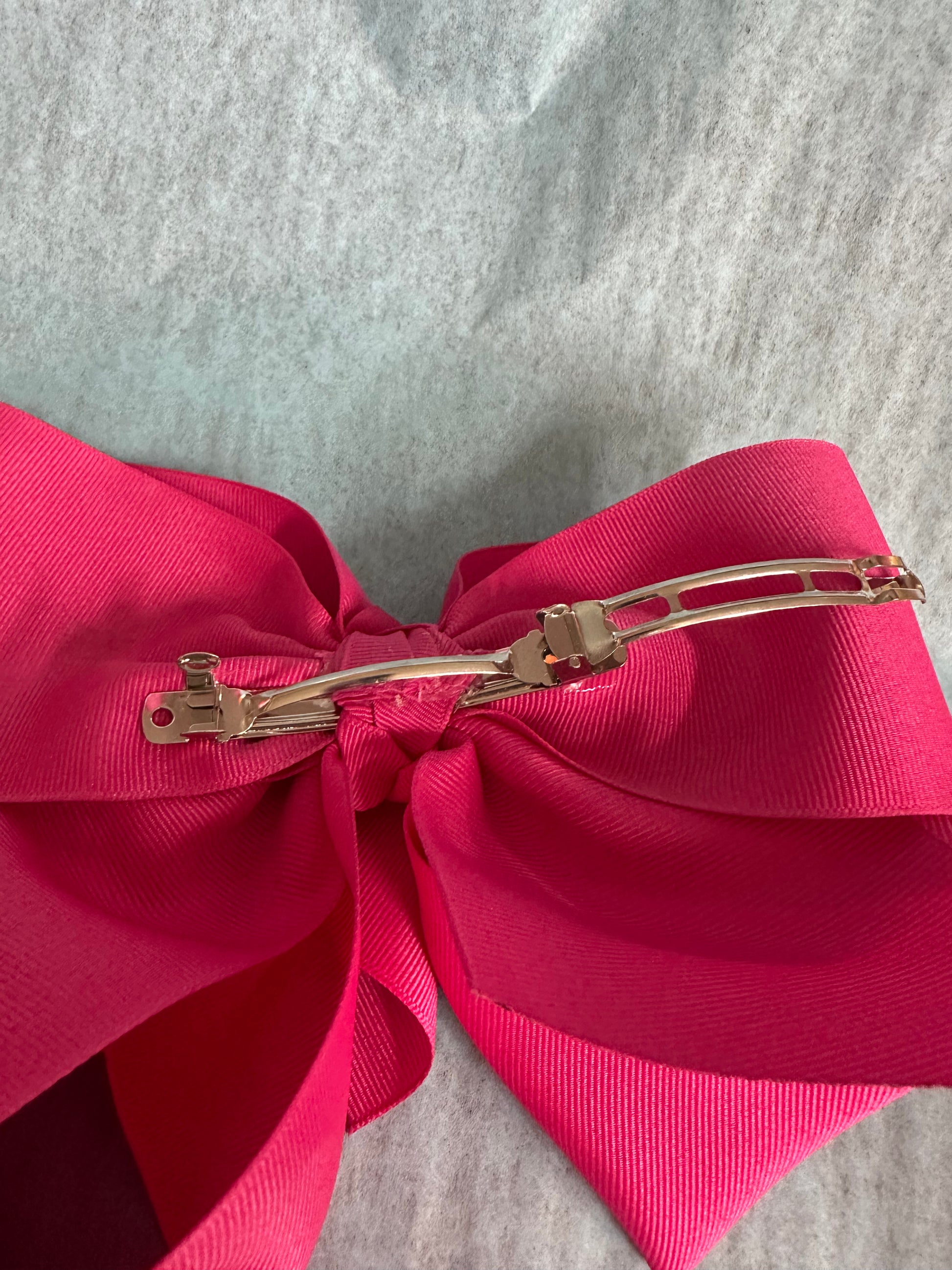 Pink bow hair clip on a gray background