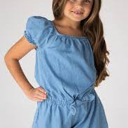 Young girl wearing a blue denim romper against a white background