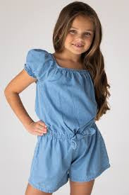 Young girl wearing a blue denim romper against a white background