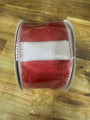 A roll of red grosgrain ribbon with a white center stripe and white stitched edges, wrapped in clear protective plastic, resting on a wooden surface.