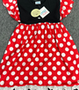 A children's dress laid flat on a gray textured surface, featuring a red and white polka-dot skirt, a black bodice, and matching red and white polka-dot ruffled shoulder straps.