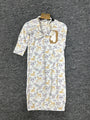 A baby sleep sack with a white background, featuring a repeating pattern of yellow deer and purple flowers, hanging on a black hanger against a dark gray textured carpet.