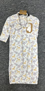 A baby sleep sack with a white background, featuring a repeating pattern of yellow deer and purple flowers, hanging on a black hanger against a dark gray textured carpet.