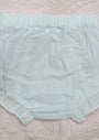 A pair of light mint green baby bloomers with eyelet lace trim, laid flat on a pink quilted blanket.
