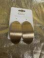 A pair of large oval drop earrings with a brushed gold finish, attached to a white display card labeled 'Cloie Jewelry & Crafts' and placed on a textured gold surface.