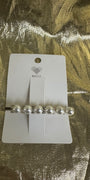 A silver barrette hair clip with five white faux pearls and rhinestone accents, displayed on a white Waffle brand card over a textured gold foil background.