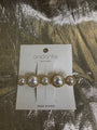Andante gold and pearl hair clip on a white display card, photographed on a textured gold foil background.