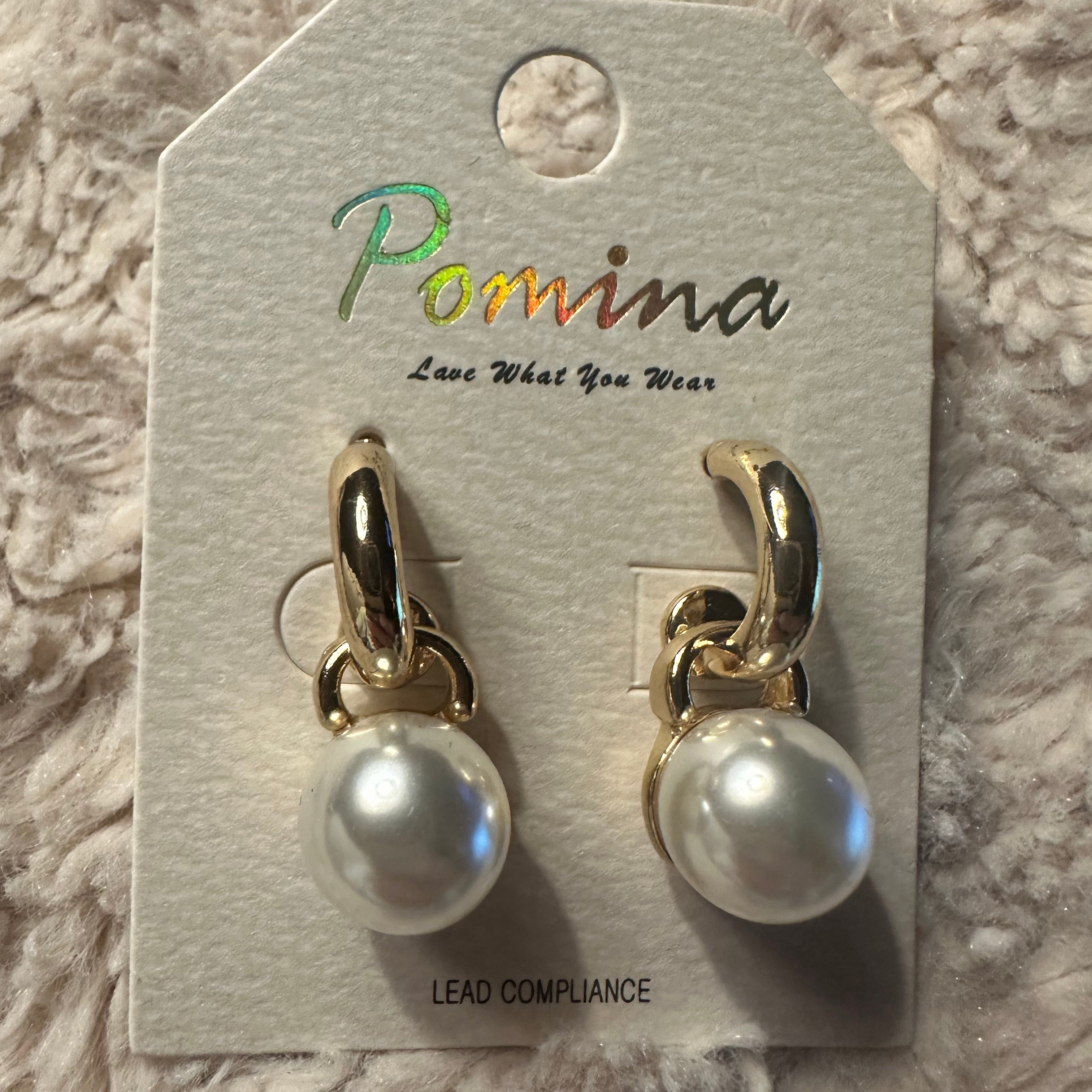 Large pearl dangle earrings on a white fluffy background
