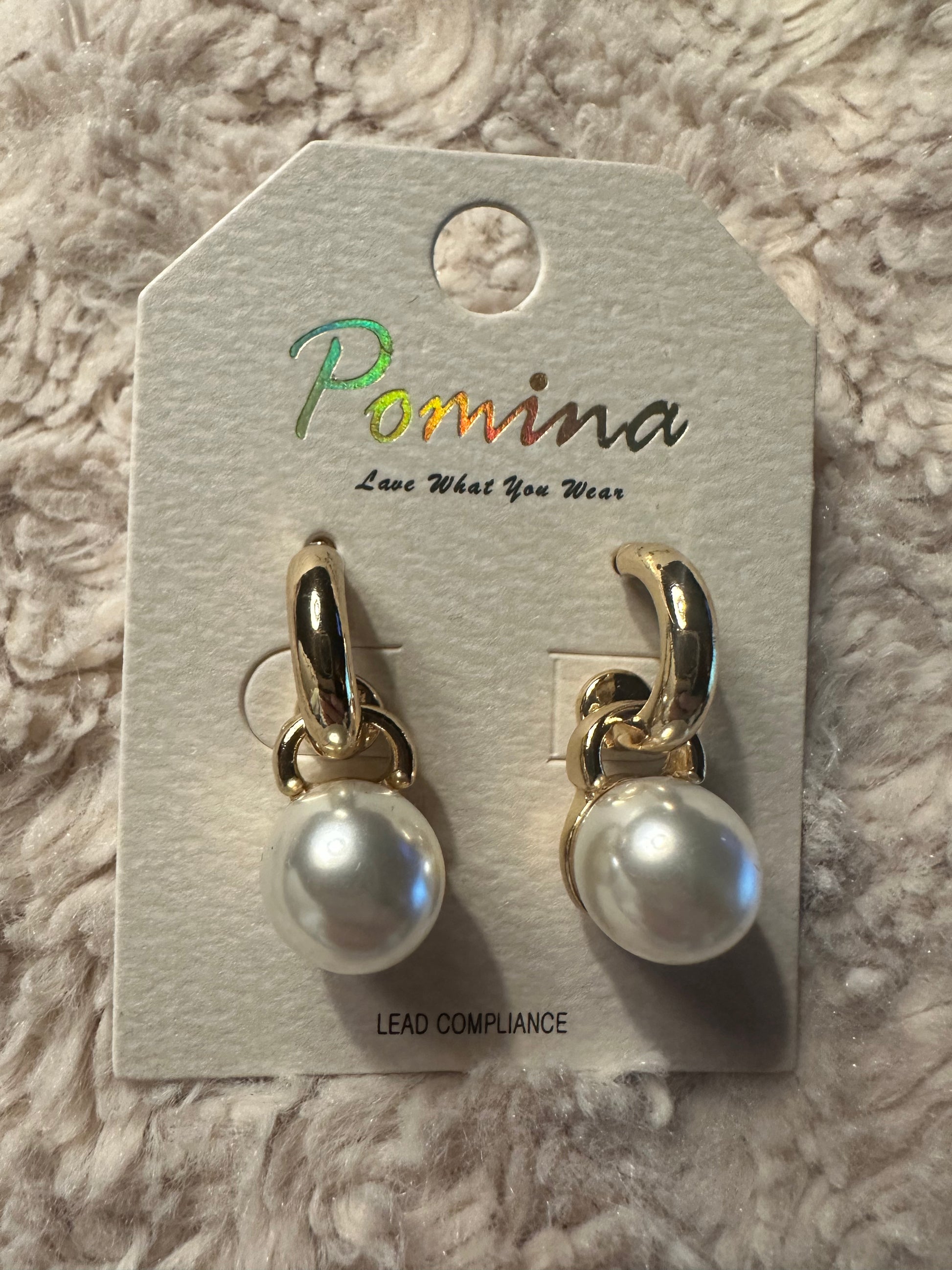 Large pearl dangle earrings on a white fluffy background
