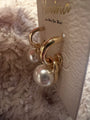Large Pearl dangle  gold earrings with post backs from side view on white fluffy background