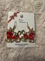 Sleighs earrings filled with gifts on white card with "Merry Christmas" in cursive and red and gold bow