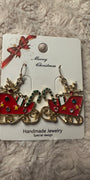 Sleighs earrings filled with gifts on white card with "Merry Christmas" in cursive and red and gold bow