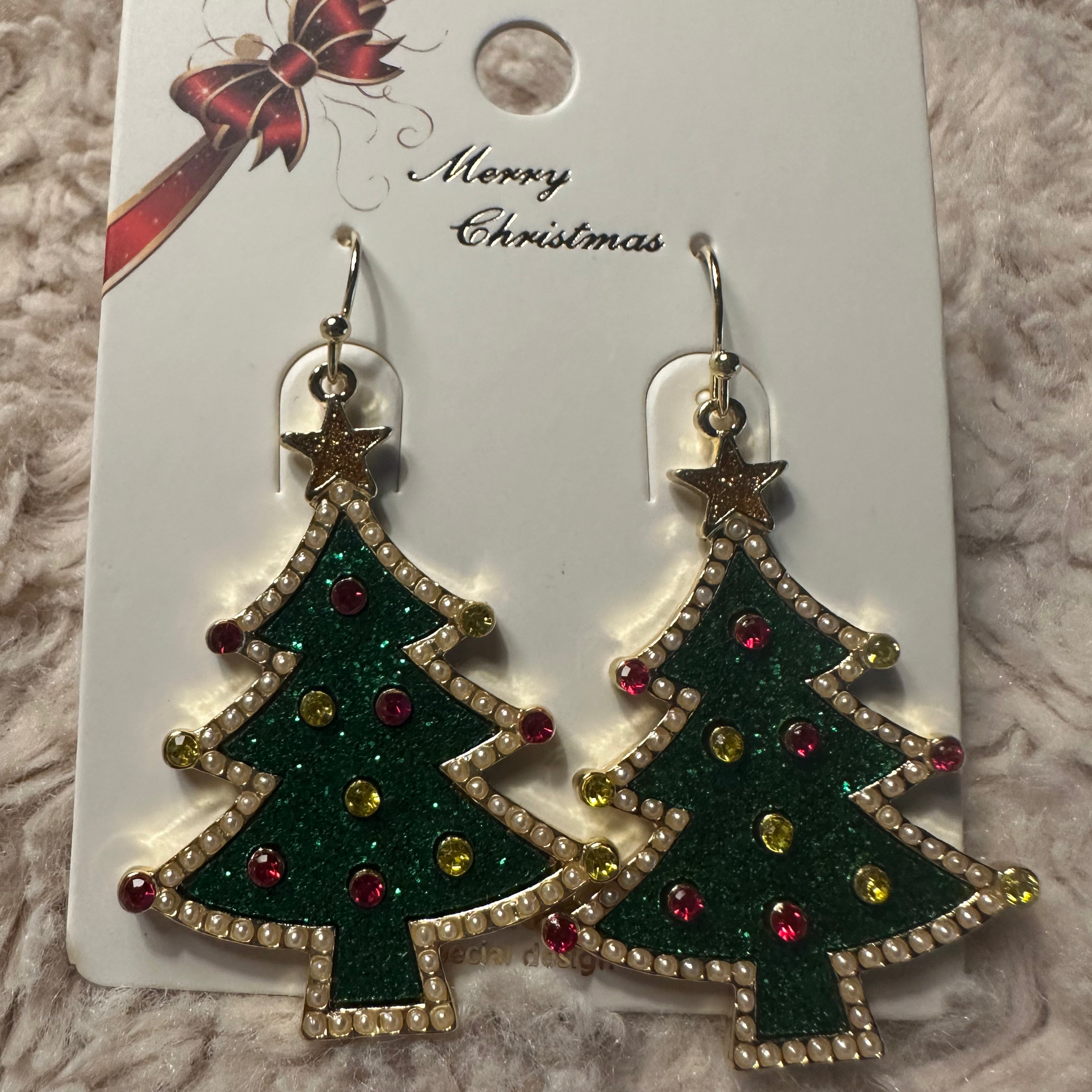 Christmas tree earrings with star on top and red and gold ornaments on white card saying Merry Christmas with red and gold bow