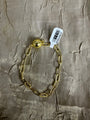 A gold chain bracelet with a polished ball clasp, laid flat on a textured beige fabric background with a white product tag attached.