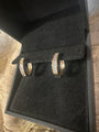 A pair of gold hoop earrings with clear pavé stones, displayed on a black velvet jewelry box.