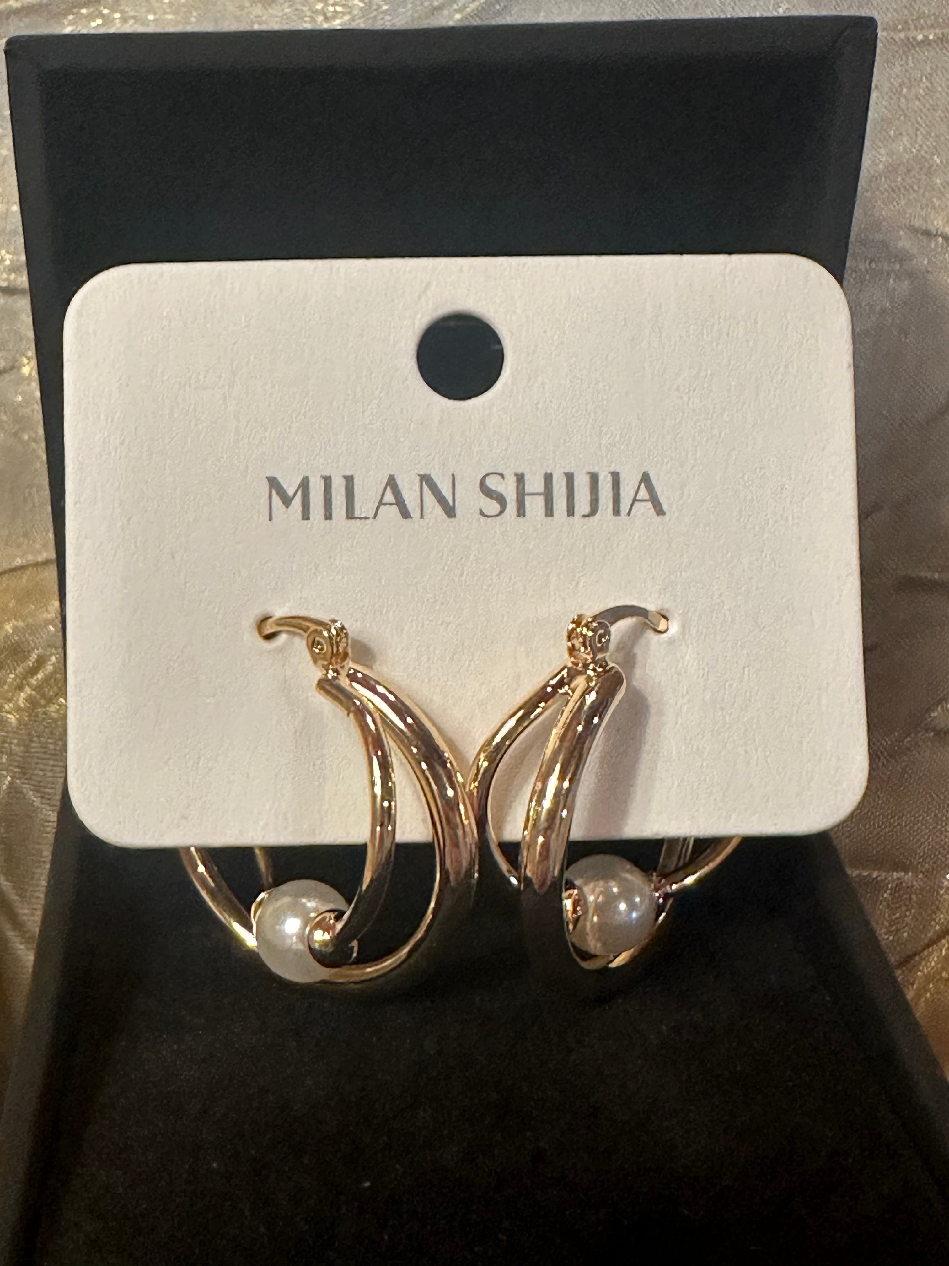 Gold crescent hoop earrings with a small white pearl, displayed on a white card labeled 'MILAN SHIJIA' inside a black jewelry box.