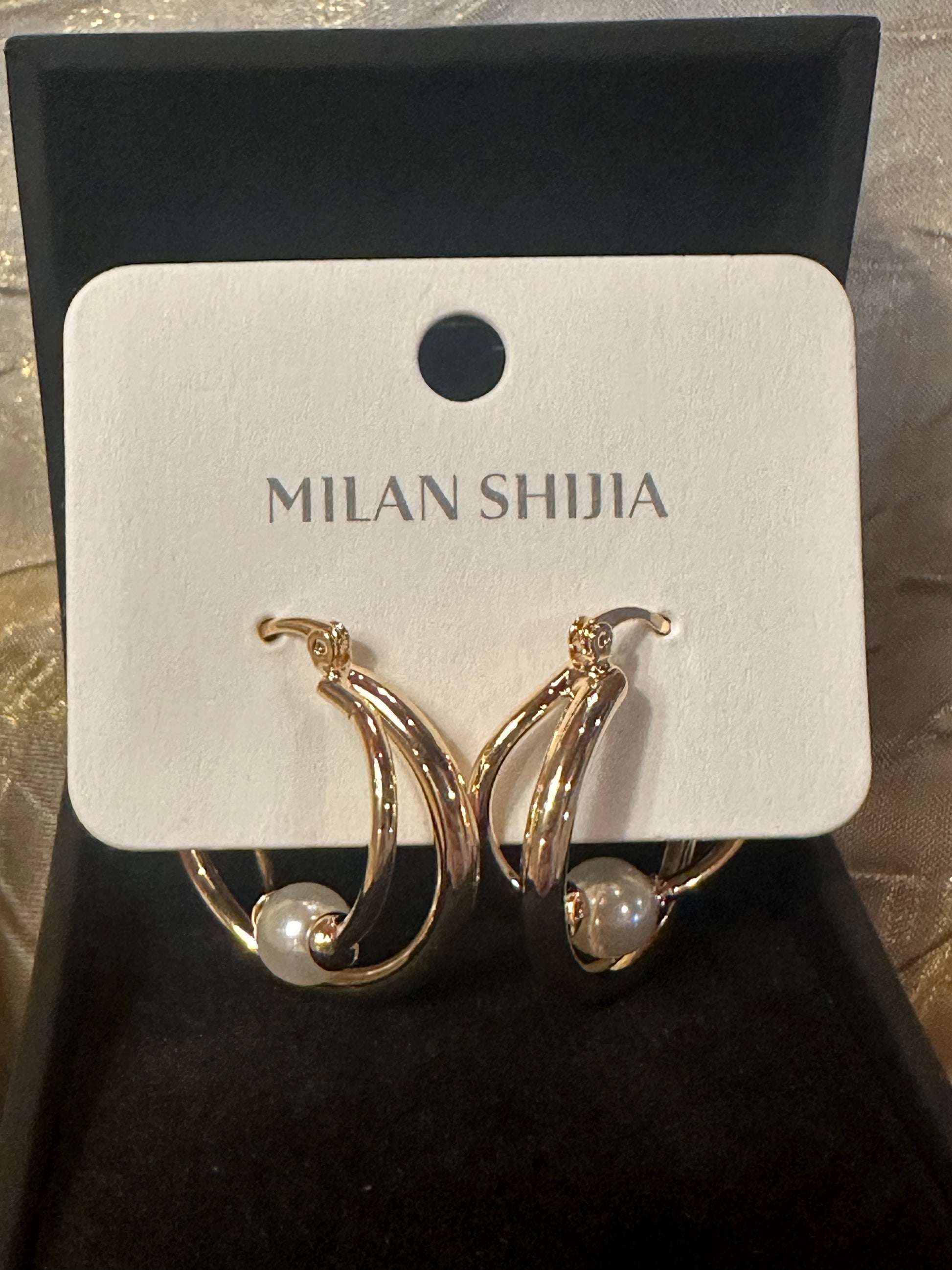 Gold crescent hoop earrings with a small white pearl, displayed on a white card labeled 'MILAN SHIJIA' inside a black jewelry box.