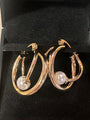 A pair of gold hoop earrings with a white pearl dangling from each hoop, displayed inside a black jewelry box.