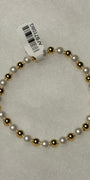 A beaded stretch bracelet featuring alternating white faux pearls and polished gold-toned beads, with a white paper tag attached.