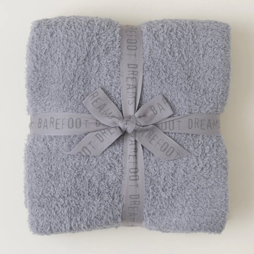 Folded gray blanket with a ribbon and 'Barefoot Dreams' branding on a white background