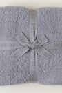Folded gray blanket with a ribbon and 'Barefoot Dreams' branding on a white background