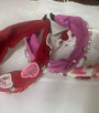 Three decorative headbands, one red . one white and one pink with heart and peaarl designs, on a white surface.