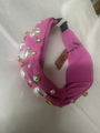 Pink headband with pearl-like beads and gold accents on a white background