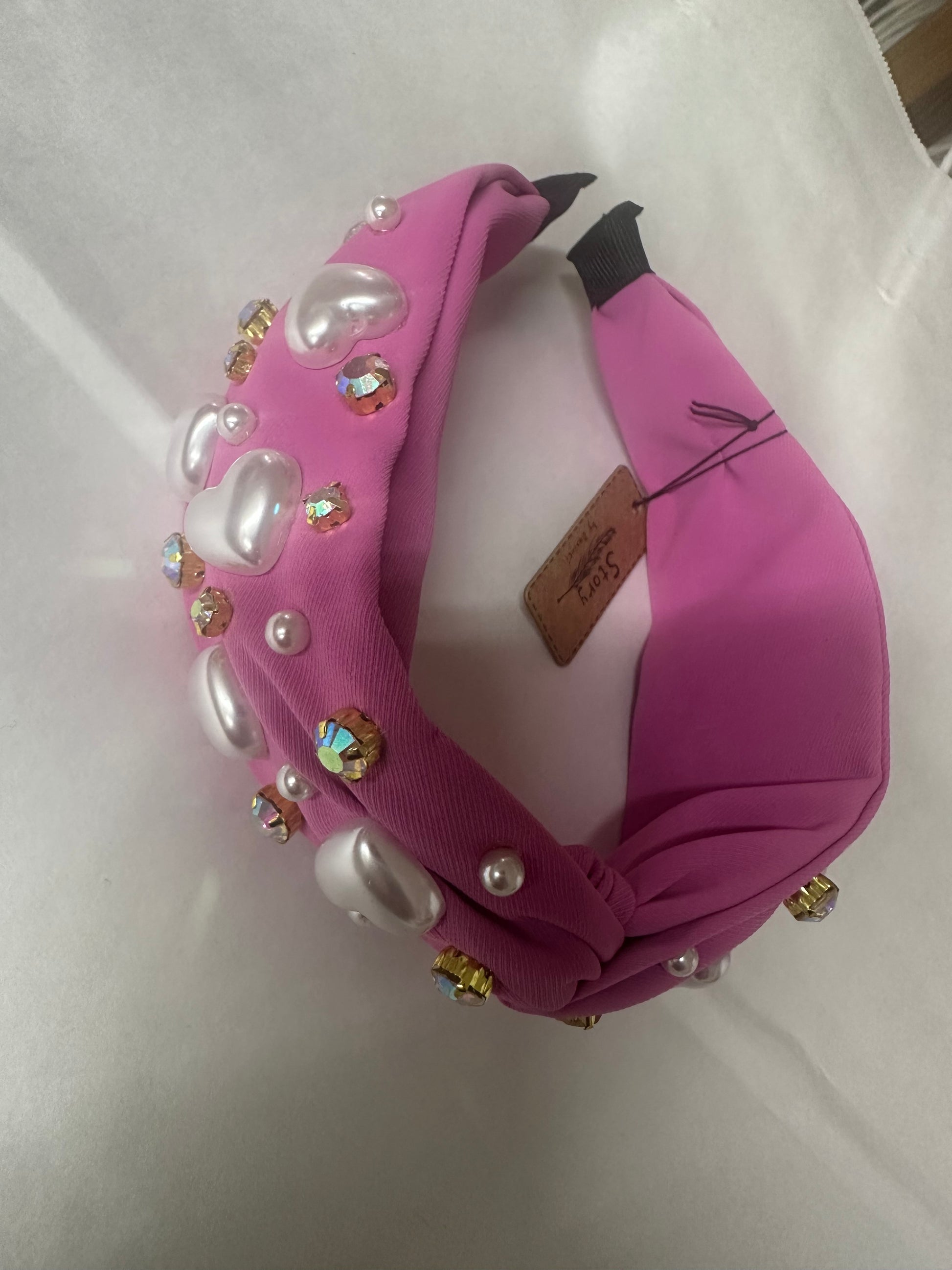 Pink headband with pearl-like beads and gold accents on a white background