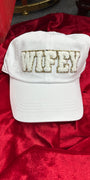 White cap with 'Wifey' embroidery on a red fabric background