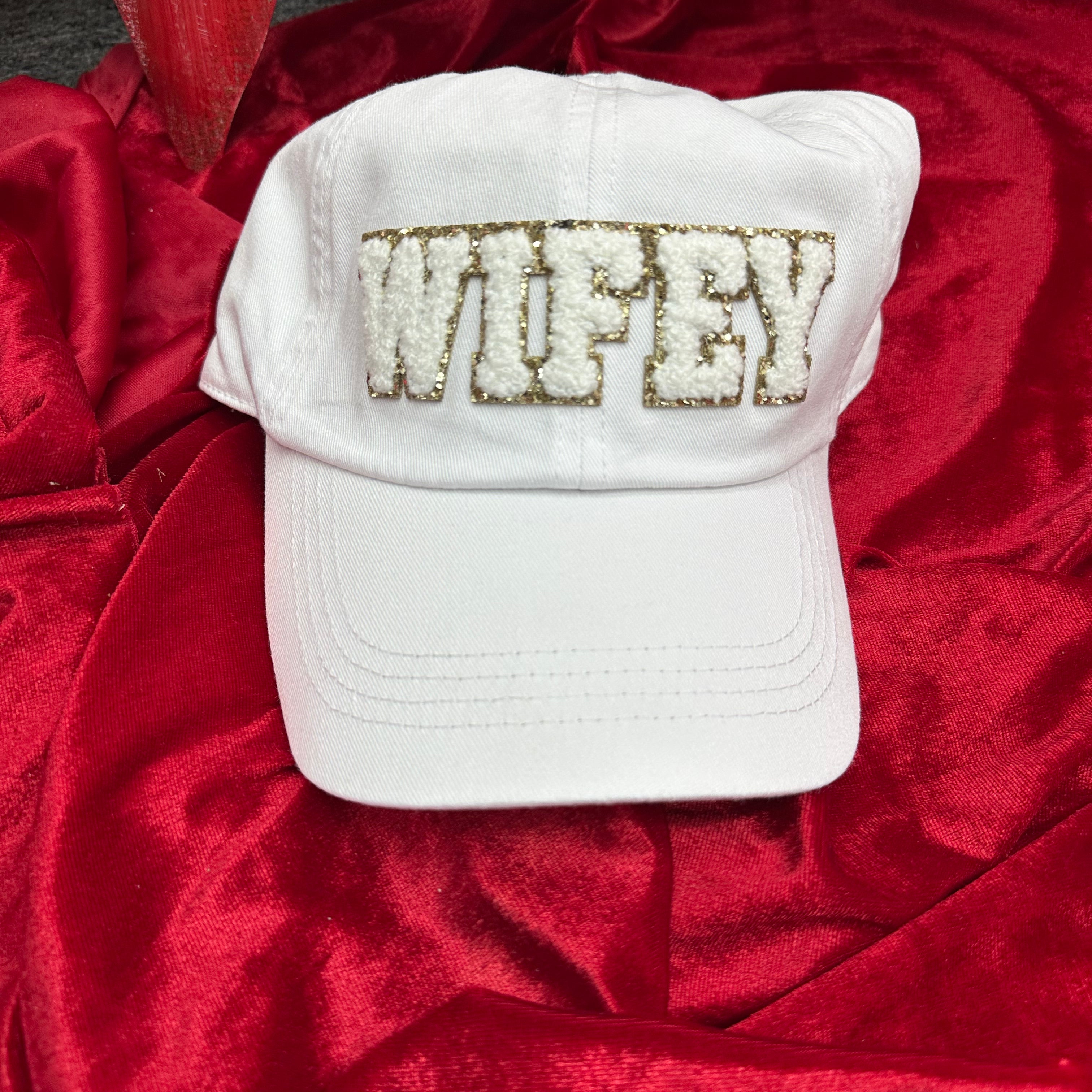 White cap with 'Wifey' embroidery on a red fabric background