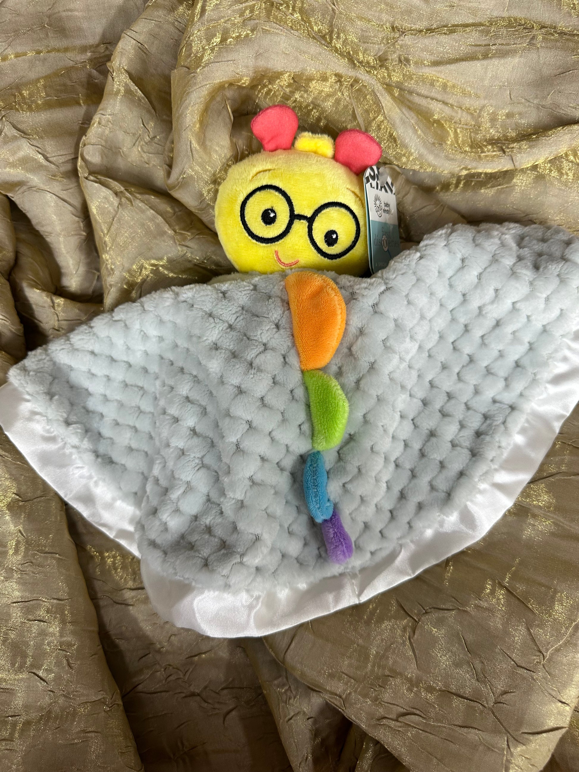 Toy bee with a colorful body and a white fuzzy blanket on a textured surface