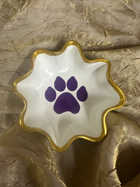Decorative dish with a purple paw print design on a textured gold surface