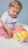 Baby playing with a soft toy on a light blue background