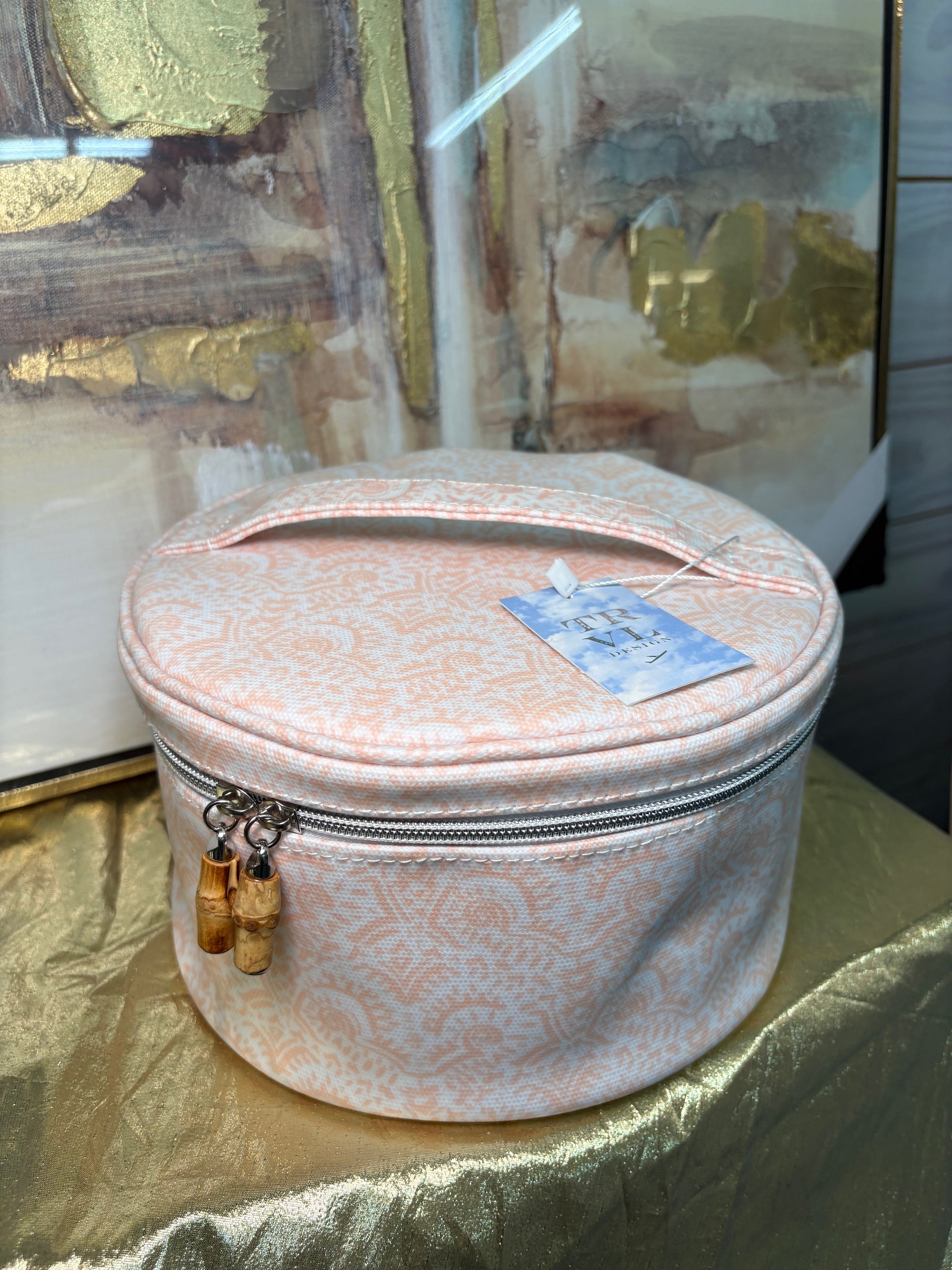 Round pink jewelry box with a gold zipper on a reflective surface