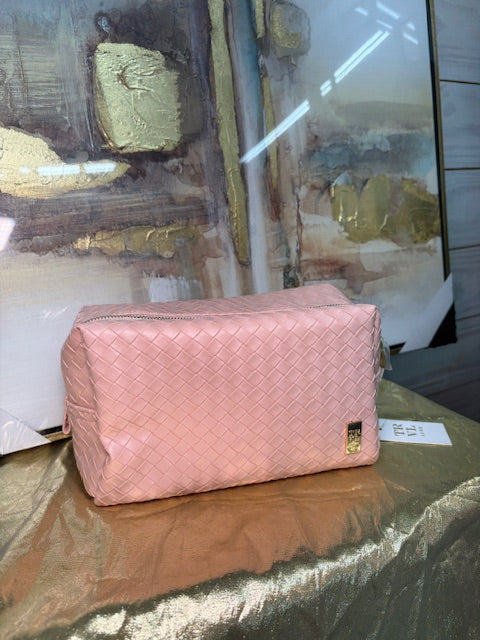 Pink quilted bag on a reflective surface with a blurred background