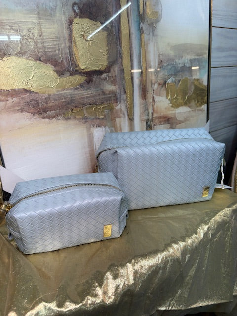 Two textured gray bags on a textured surface with a blurred background