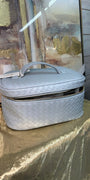 Gray quilted handbag on a textured surface with abstract art in the background
