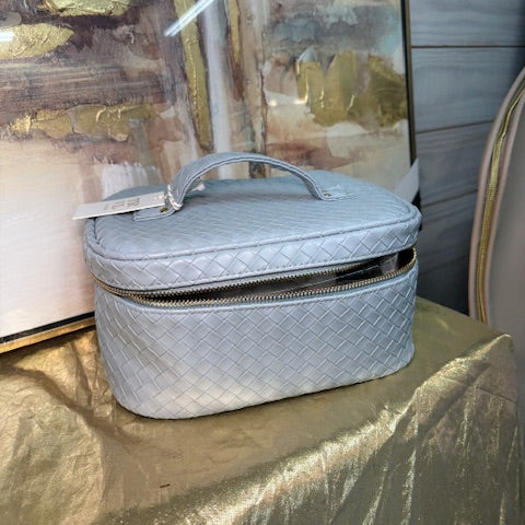 Gray quilted handbag on a textured surface with abstract art in the background