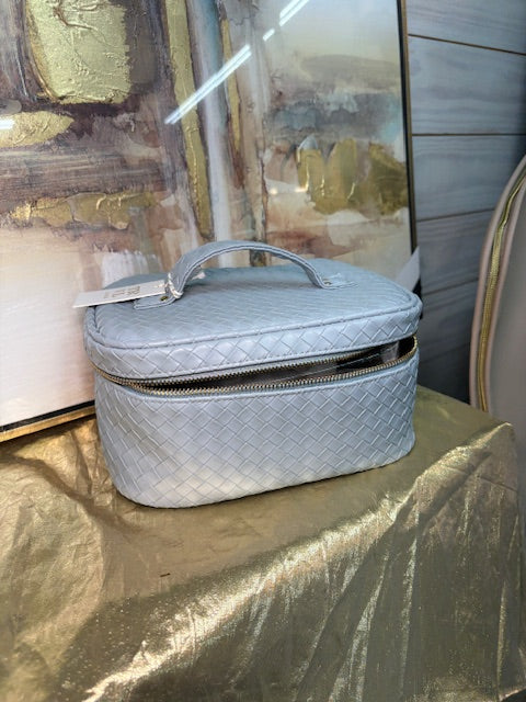 Gray quilted handbag on a textured surface with abstract art in the background