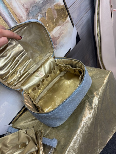 Gold makeup case with blue interior on a marble surface
