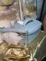Blue cosmetic bag with a visible brand tag on a reflective gold surface