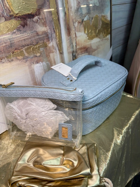 Blue cosmetic bag with a visible brand tag on a reflective gold surface