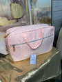 Pink patterned bag on a reflective surface with a blurred background