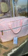 Pink patterned bag on a reflective surface with a blurred background