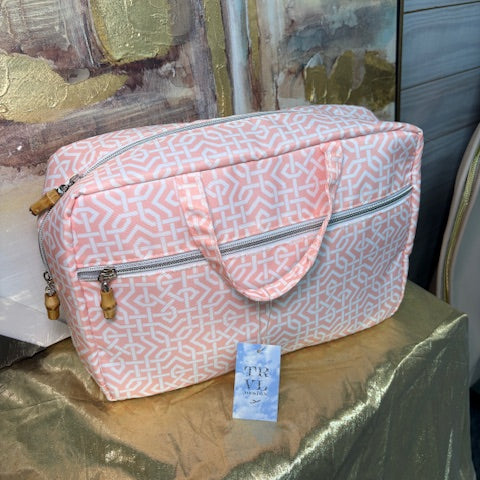 Pink patterned bag on a reflective surface with a blurred background