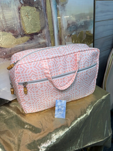 Pink patterned bag on a reflective surface with a blurred background