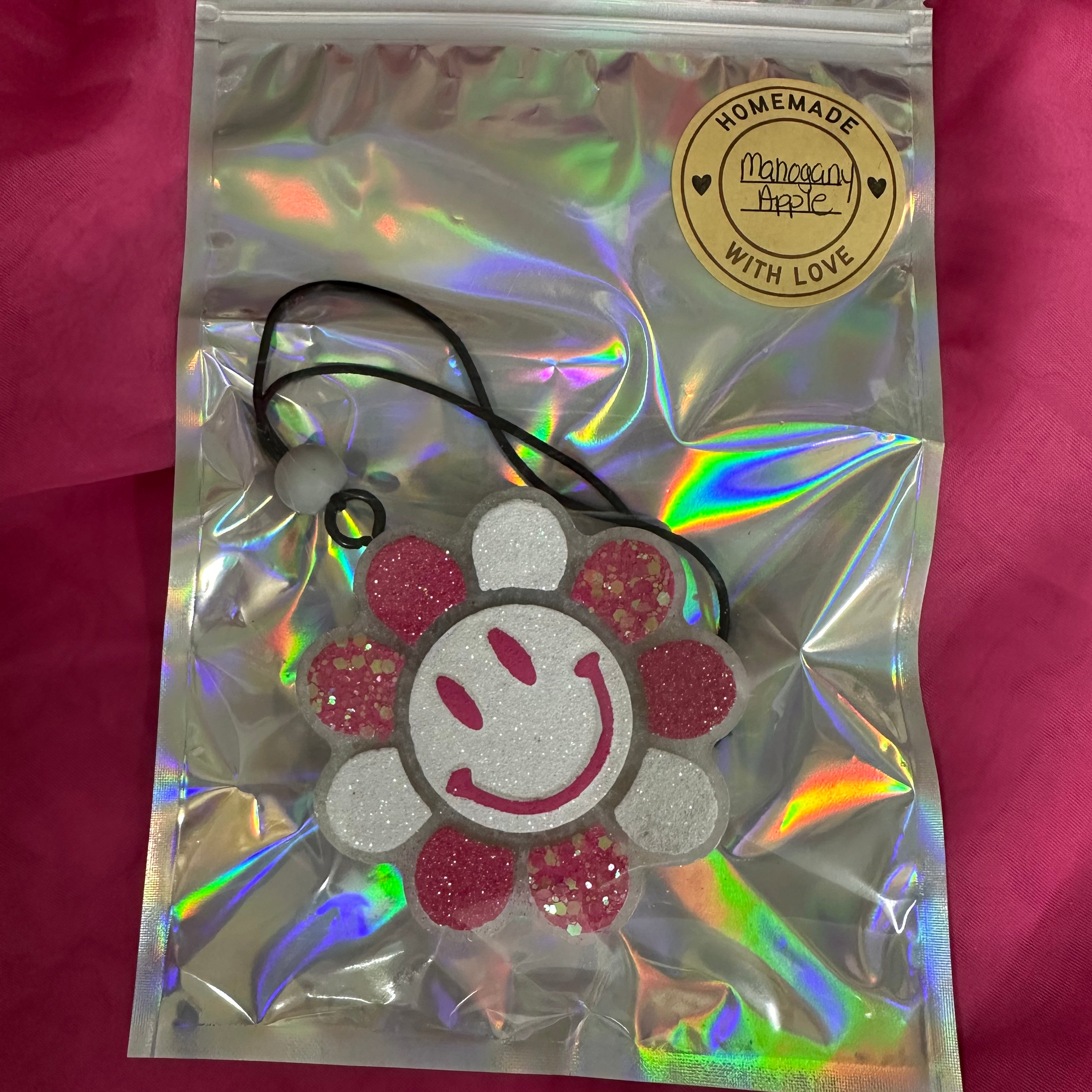 Holographic bag with a decorative item on a pink background