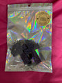 Black glittery scented crosses on a reflective packaging on a pink background