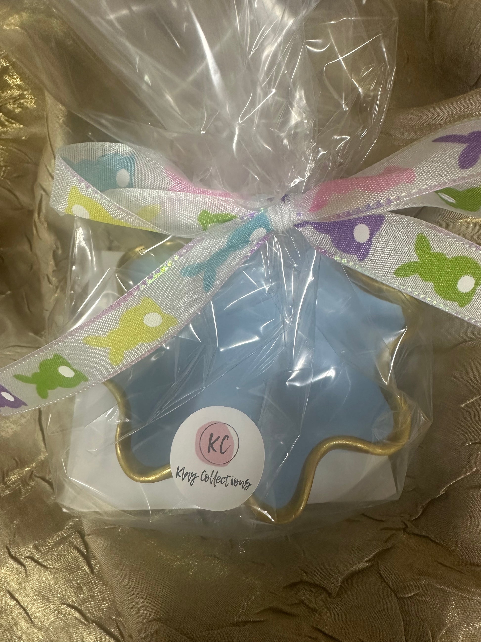 Trinket dish in blue with colorful ribbon packaging on a brown surface
