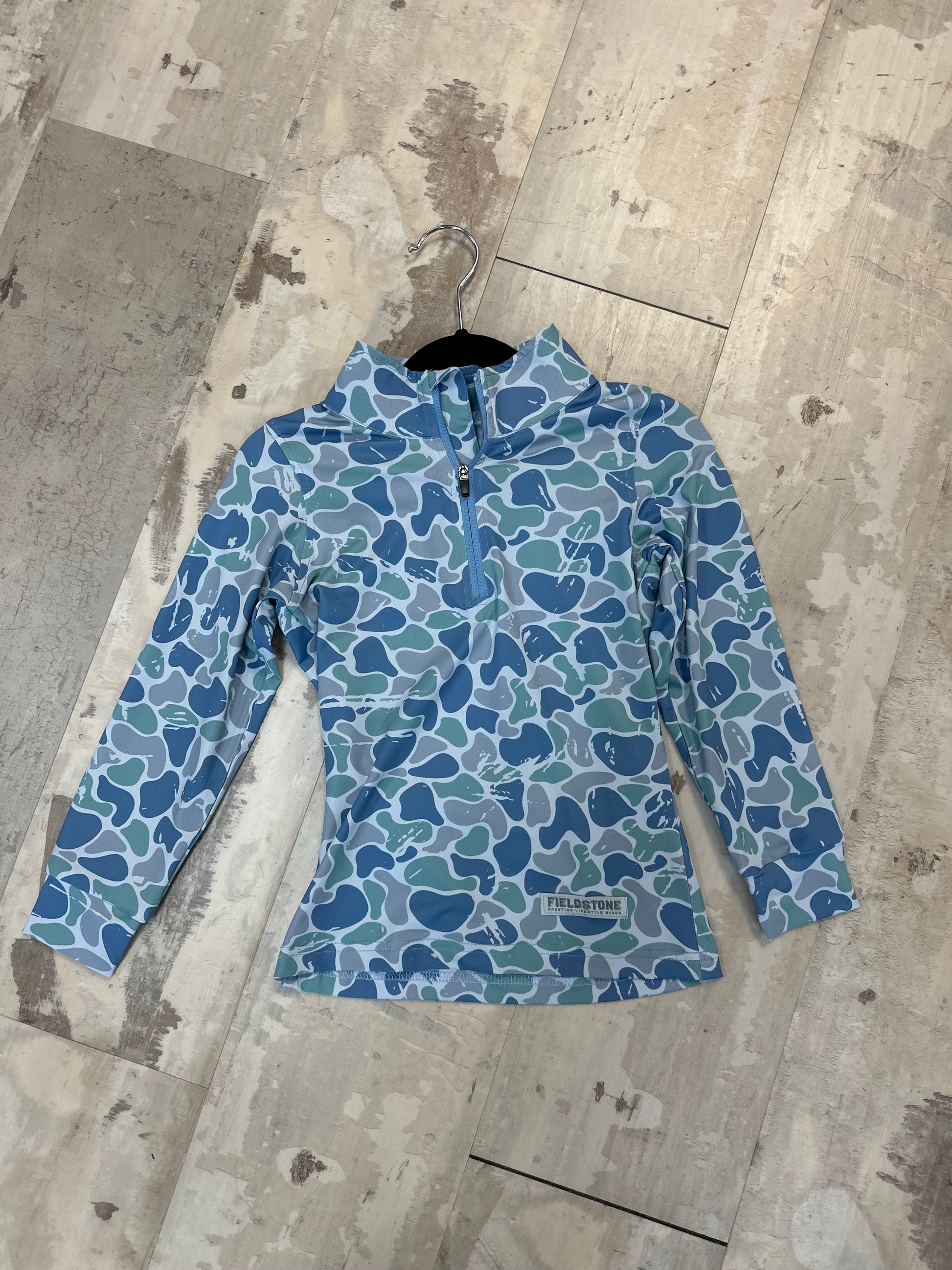 Blue camouflage-patterned jacket on a wooden floor